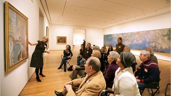 IMAGE DESCRIPTION: Francesca Rosenberg, who is the Director of Community, Access, and School Programs, Department of Education at the Museum of Modern Art, leads an in-gallery program for people with dementia and their caregivers in the galleries of the museum.